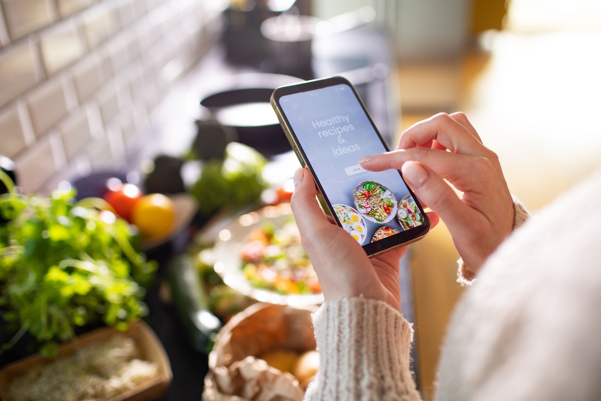 Young adult woman using a dieting app on her smart phone to prepare a healthy salad